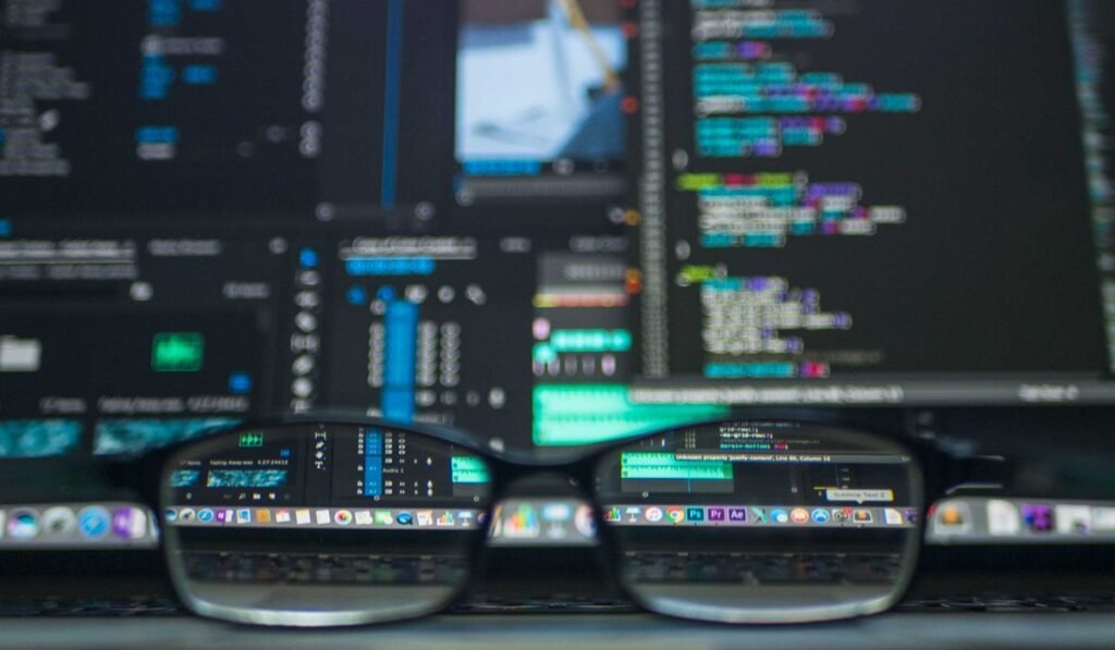 Código y datos reflejados en unas gafas frente a un ordenador