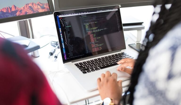 Desarrolladora trabajando con varios monitores y herramientas digitales
